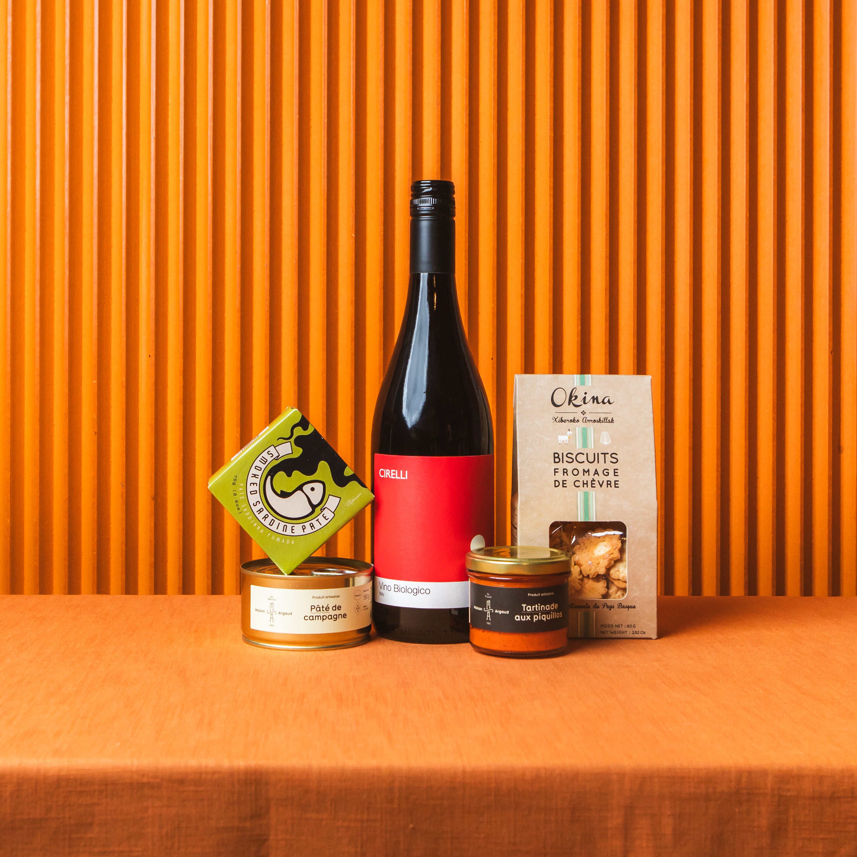 Wine bottle with snacks and a box against an orange background